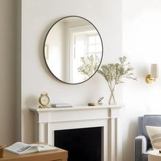 a living room filled with furniture and a round mirror on the wall above a fireplace