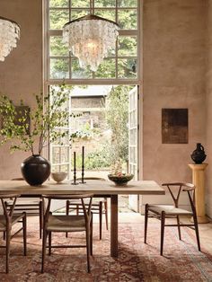 a dining room table with chairs and a chandelier hanging from it's ceiling