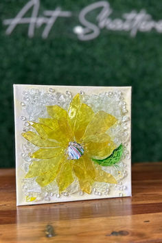 a yellow flower is sitting on a wooden table