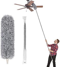 a man is holding a broom and cleaning the floor with a mop in front of a ceiling fan