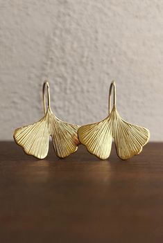 These pretty dangling earrings belong to the GINKGO collection by Calcagnini Gioielli. The leaves are handmade using a plate of 18 kt gold which is subsequently laminated, shaped and engraved. This type of craftsmanship makes each jewel unique and gives it brightness, lightness and resistance. The height of the earring is approximately 3cm, the width is approximately 2.5cm, the finish is shiny. The earrings will be shipped in a beautiful gift box. N.B .: The timing of the realization of this jew Ginko Leaf Earrings, Leaf-shaped Yellow Gold Brass Jewelry, Modest Mom, Beauty Magic, Ginkgo Biloba, Dangling Earrings, Beautiful Gift Boxes, Leaf Earrings, Hand Engraving