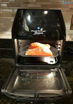 salmon being cooked in an air fryer on top of a granite counter with the door open