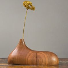 a wooden vase with a flower sticking out of it's side on a table