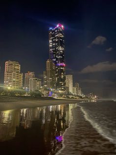 the city is lit up at night on the beach