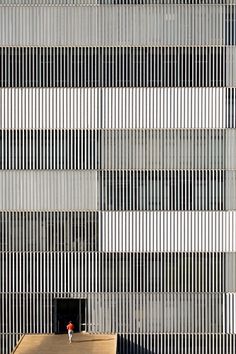 a black and white photo of a building with vertical lines on the wall behind it