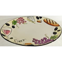 an oval platter with different types of food and wine on the rim, decorated with black stones