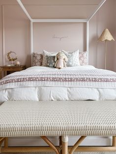 a white bed with pink walls and pillows