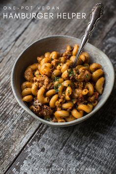 a bowl filled with pasta and meat on top of a wooden table