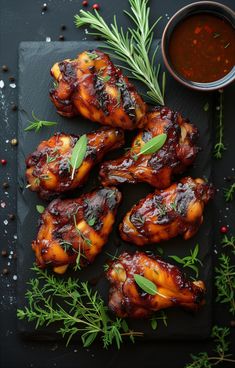 grilled chicken wings with herbs and ketchup on a black slate platter