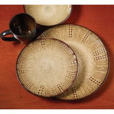 three plates and two cups sitting on a wooden table next to each other with the same pattern