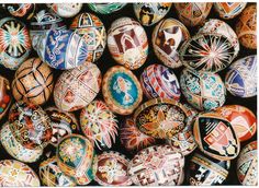 many different colored eggs are stacked on top of each other, with designs painted on them