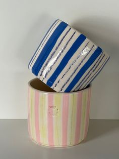 two ceramic bowls sitting side by side on a counter top, one is blue and the other has pink and yellow stripes