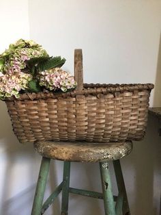 a wicker basket sitting on top of a wooden stool next to a flower pot