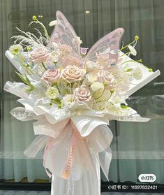 a bouquet of white flowers and pink butterflies on display in front of a store window