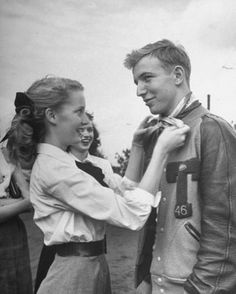 an old black and white photo of a man helping a woman put on her tie