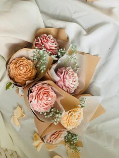 three flowers are wrapped in brown paper on a bed