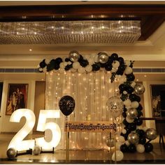 a decorated room with balloons and lights on the wall, number twenty five in front of it