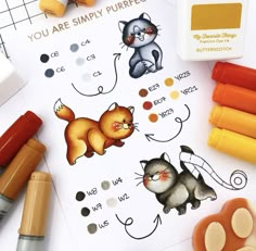 some crayons are laying on top of a sheet of paper with pictures of cats and kittens