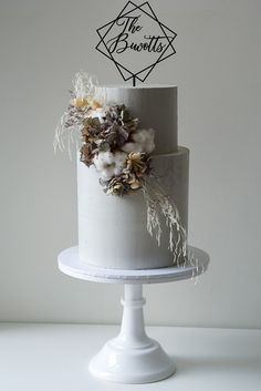 a three tiered white cake with dried flowers on top