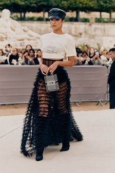 a woman standing in front of a crowd wearing a black skirt and white t - shirt