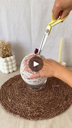 a person is using scissors to cut yarn on a ball with crochet doily