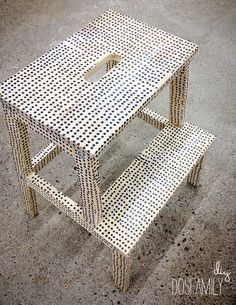 a white table and two benches sitting on the ground in front of a building that has dots all over it