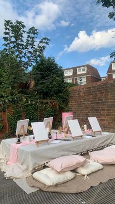 an outdoor table with paintings and pillows on it