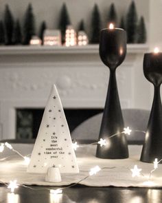 three black candlesticks sitting on top of a table next to a christmas tree