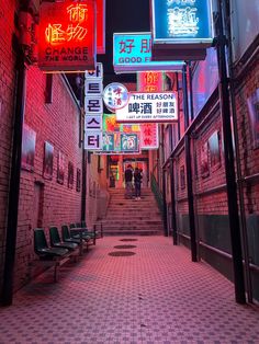 an alley way with neon signs and benches