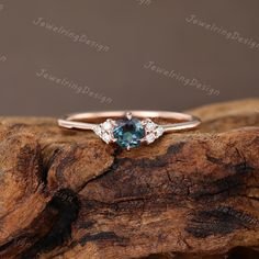 an engagement ring with blue and white diamonds on top of a piece of drift wood