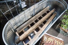 a metal tub filled with wooden planks next to a sign that says happy frog