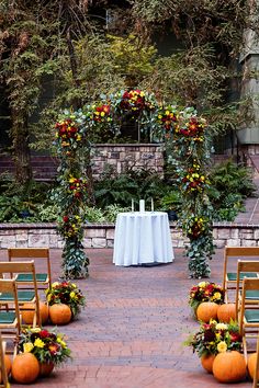 an outdoor ceremony set up with pumpkins and flowers