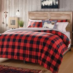 a bed with plaid comforter and pillows in a room next to a large window