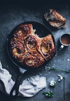 a pan filled with pastry next to a cup of coffee and napkin on top of a table