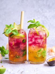 two glasses filled with fruit and minty drinks on top of a white table next to an avocado