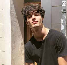 a young man standing in front of a building with his eyes closed and looking off to the side