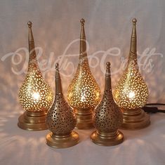 three gold vases with lights in them on a white background