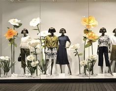 mannequins dressed in black and white outfits with flowers behind them on display