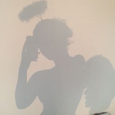 a shadow of a woman holding a cell phone to her ear and standing in front of a wall