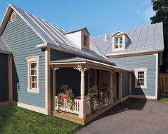 a small blue house with a porch and flower boxes on the front door is shown