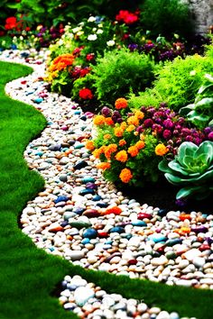 a garden filled with lots of different colored flowers and plants on top of green grass