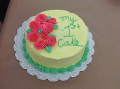 a yellow cake with green icing and red roses on top that says my 1st cake