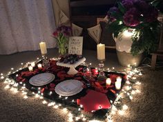 a table topped with plates and candles on top of a rug covered in red flowers