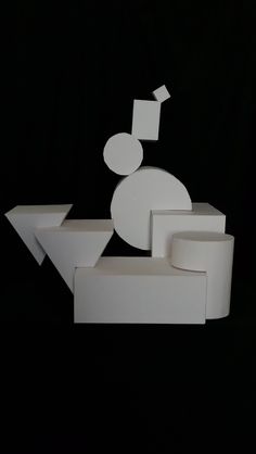 an abstract sculpture made out of white paper on top of a black surface with circles and rectangles