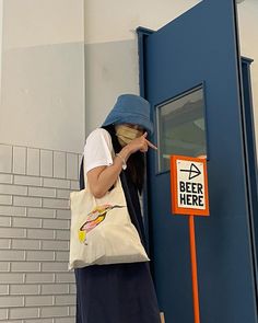 a woman standing in front of a blue door with a beer here sign on it