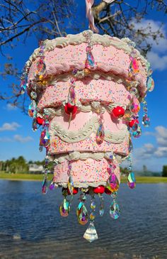 a pink cake with sprinkles hanging from it's side near the water