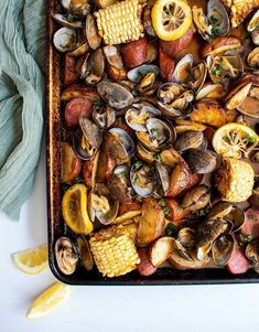 a pan filled with clams and corn on the cob