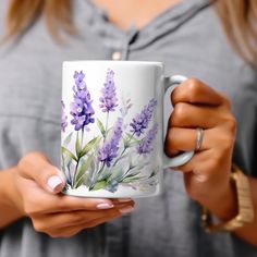 a woman holding a coffee mug with purple flowers on it