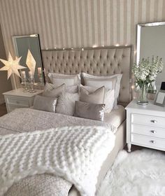 a white bed sitting next to a mirror and dresser in a room with striped walls