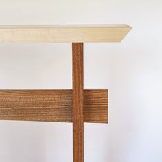 a wooden table with a cross on it and a white wall in the back ground